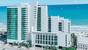 Un hôtel moderne à plusieurs étages, doté de grandes fenêtres et offrant une vue sur la plage.