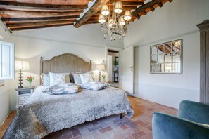 A bedroom with a large bed, a chandelier, a wooden ceiling, and a view of a window. - 10 Bedroom Luxury Villa in Lucca (Lucca)