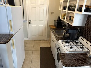 Une cuisine équipée d’un réfrigérateur, d’une cuisinière, d’un évier et de placards.