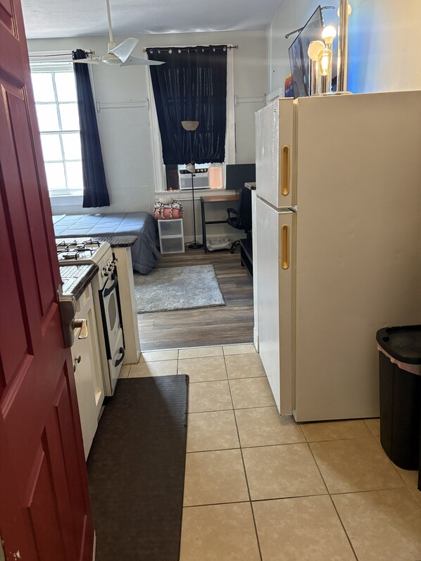 A compact kitchen with a stove, refrigerator, and a small dining area.