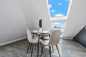 A dining area with a table set for four, a vase with black feathers, and a skylight above. - Luxury 2 Bed Penthouse With Views Over London With Free Parking (Uxbridge)