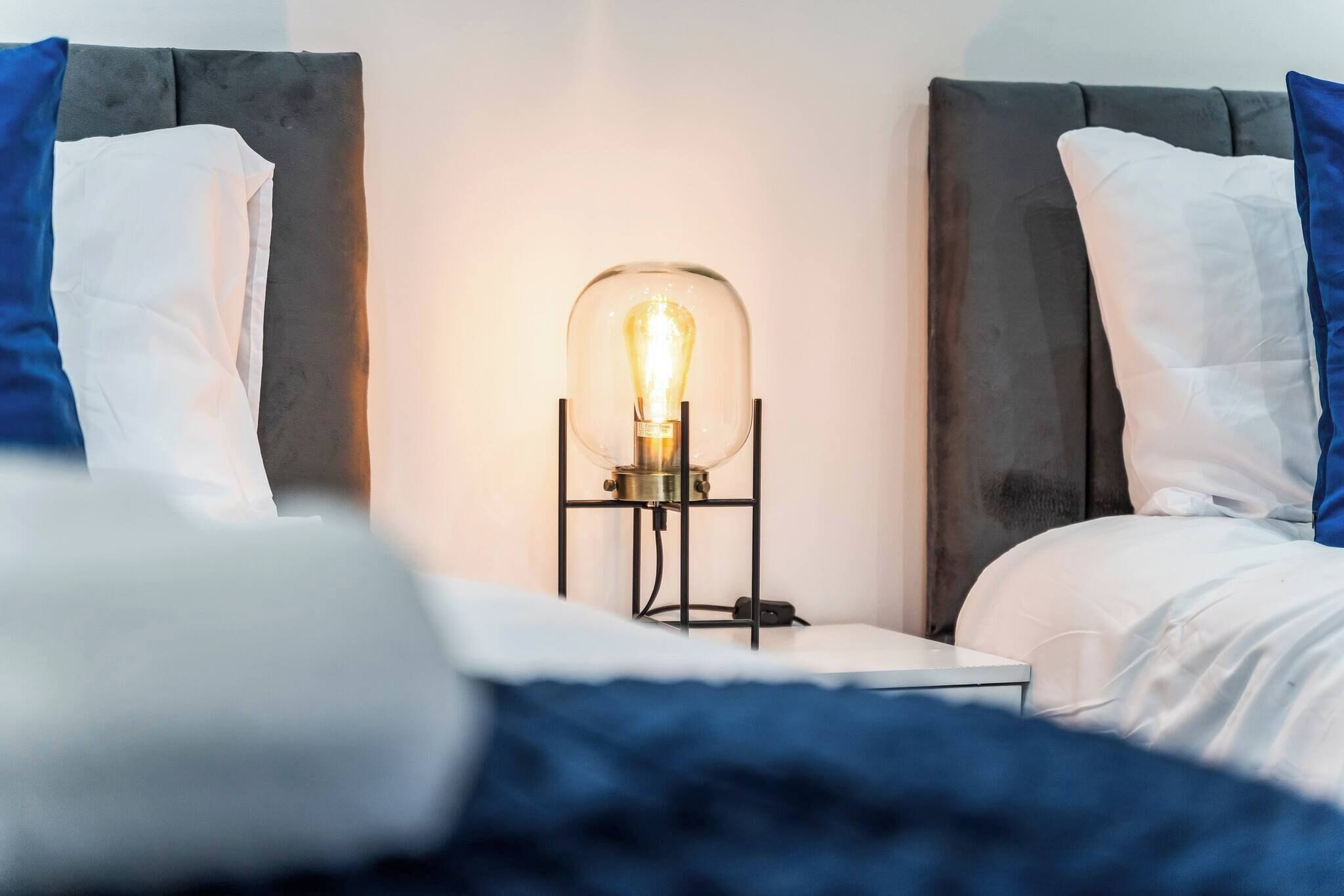 A hotel room with a bed, a nightstand with a lamp, and a headboard.