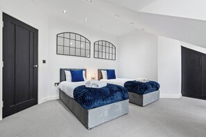 A modern bedroom with two beds, dark wood doors, and a ceiling with recessed lighting. - Luxury 2 Bed Penthouse With Views Over London With Free Parking (Uxbridge)