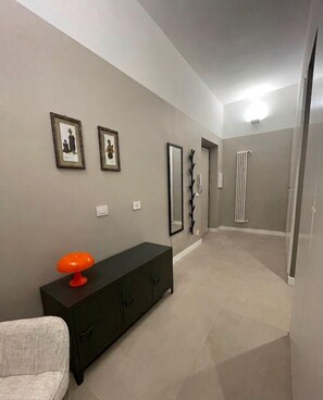 A hallway with a dark-colored cabinet, a light-colored sofa, and two framed pictures on the wall. - Marsi sunny studio (Roma)