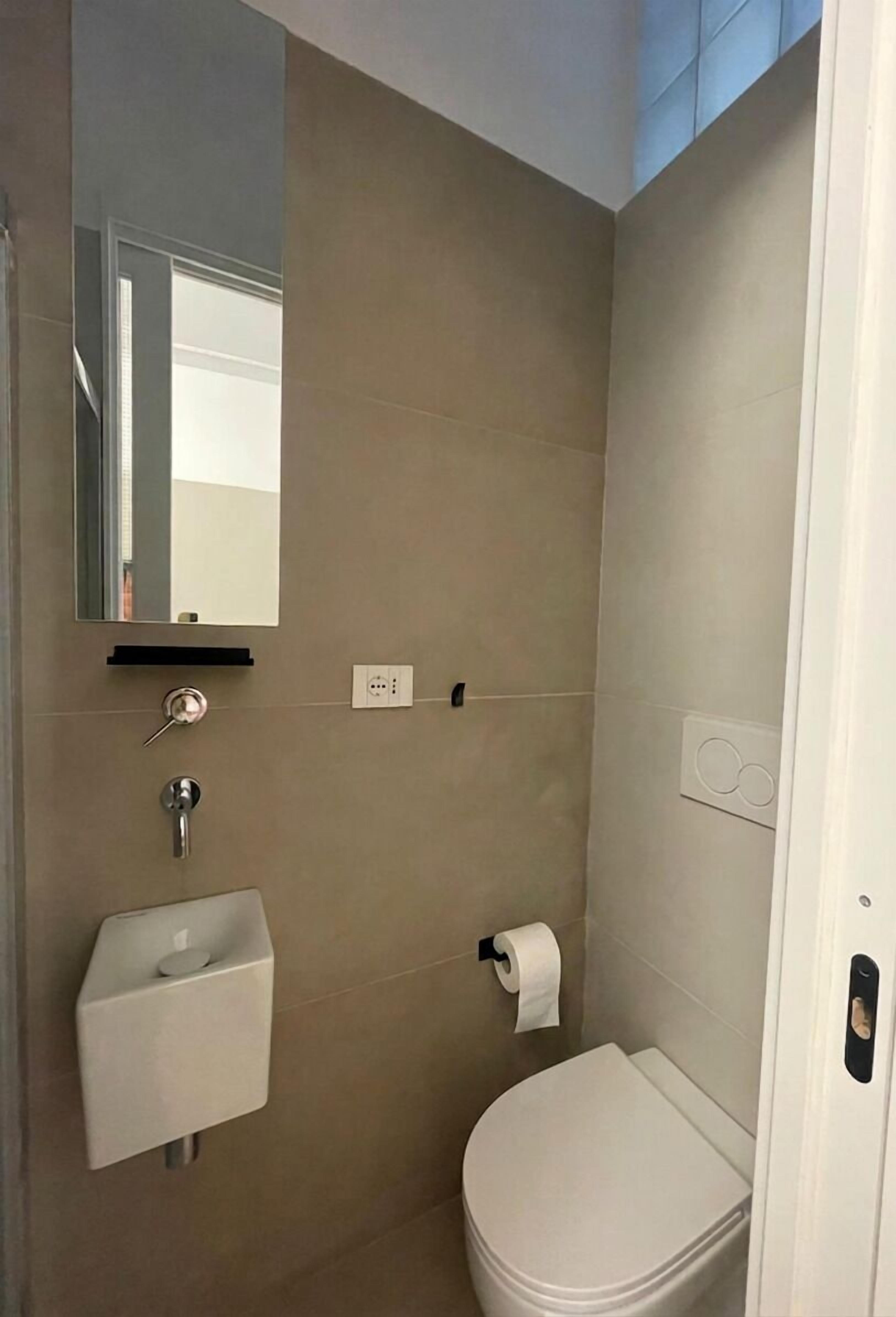 Une salle de bain équipée de toilettes, d’un lavabo, d’un miroir et d’un porte-serviettes.