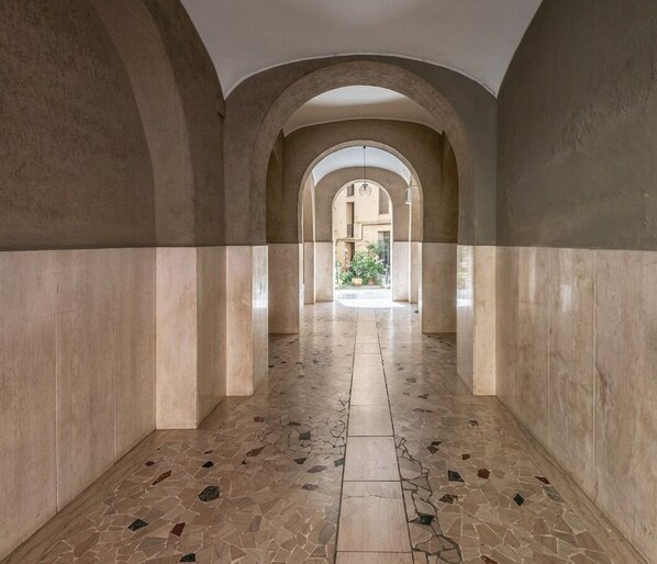 A corridor with arches, tiled flooring, and a view into a building. - Marsi sunny studio (Roma)