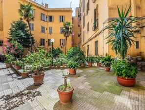 A courtyard with potted plants, a street lamp, and yellow buildings. - Marsi sunny studio (Roma)