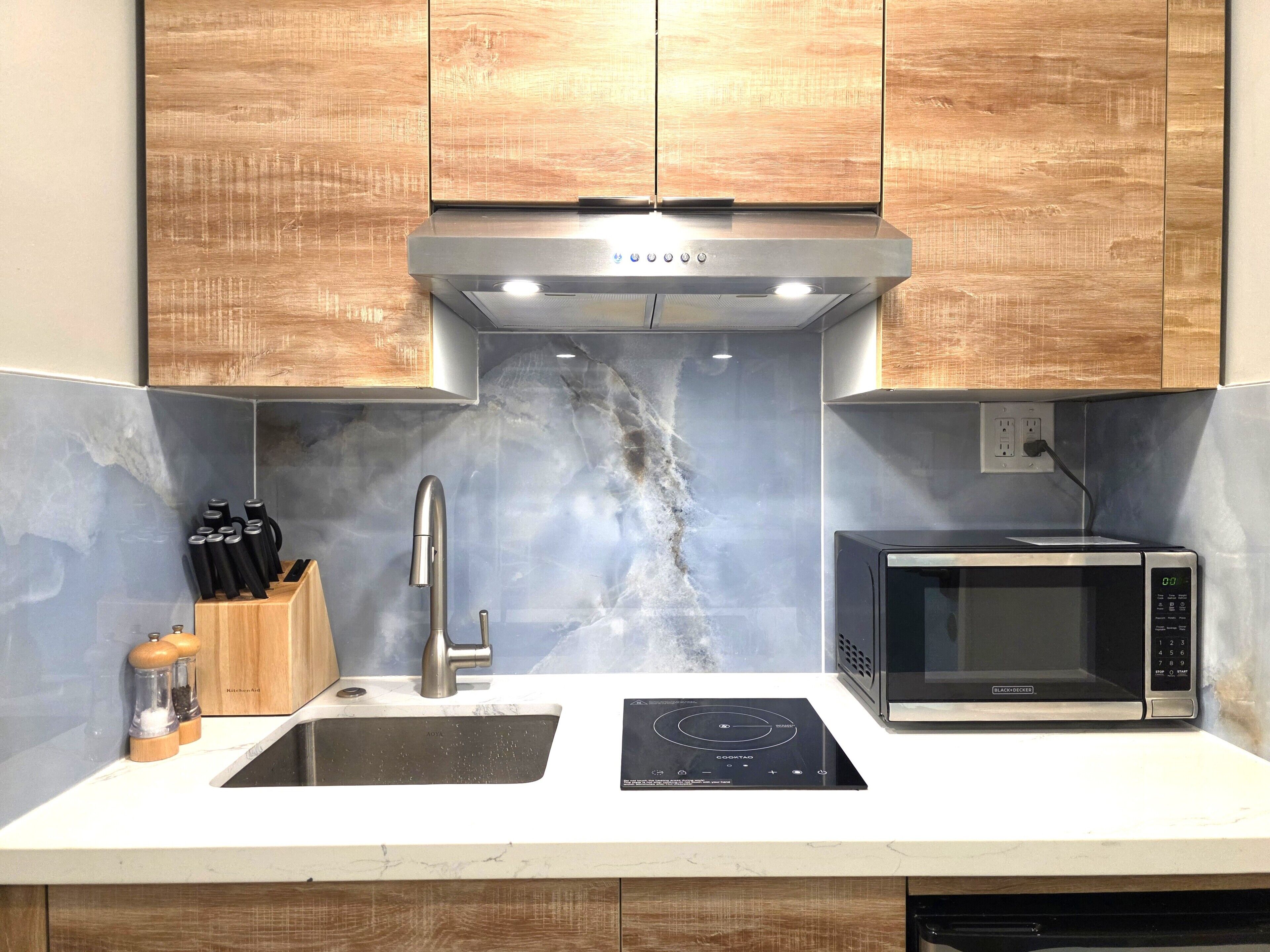 A modern kitchen with a built-in microwave, a stainless steel sink, and wooden cabinets.