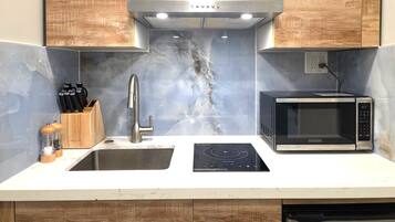A modern kitchen with a built-in microwave, a stainless steel sink, and wooden cabinets.
