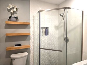Ein modernes Badezimmer mit einer Duschkabine, einer Toilette und Holzregalen mit Pflegeprodukten.