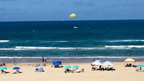 A beach with umbrellas, tents, and people. - New Listing! Beachfront 2 Bdrm Condo, Family Friendly. Make great memories here! (South Padre Island)