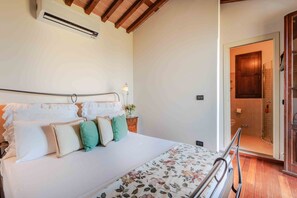 Un dormitorio con cama, mesita de noche, lámpara y una puerta que da al baño.