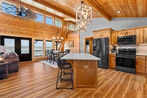 A spacious kitchen with wooden cabinets, a large island, and modern appliances. - Private Island Retreat on Weiss Lake (Cedar Bluff)