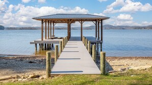 Een houten steiger die leidt naar een overdekte pergola aan een rustig meer.