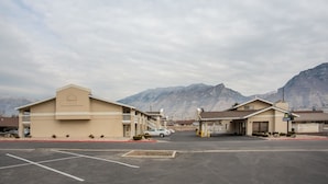Um Days Inn com estacionamento, um edifício com varanda e montanhas ao fundo.