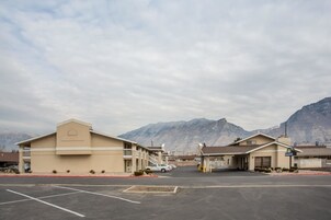 A Days Inn with a parking lot, a building with a balcony, and mountains in the background.