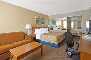 A hotel room with a bed, a sofa, a desk, a chair, a television, and a mirror. - Days Inn Provo (Provo)
