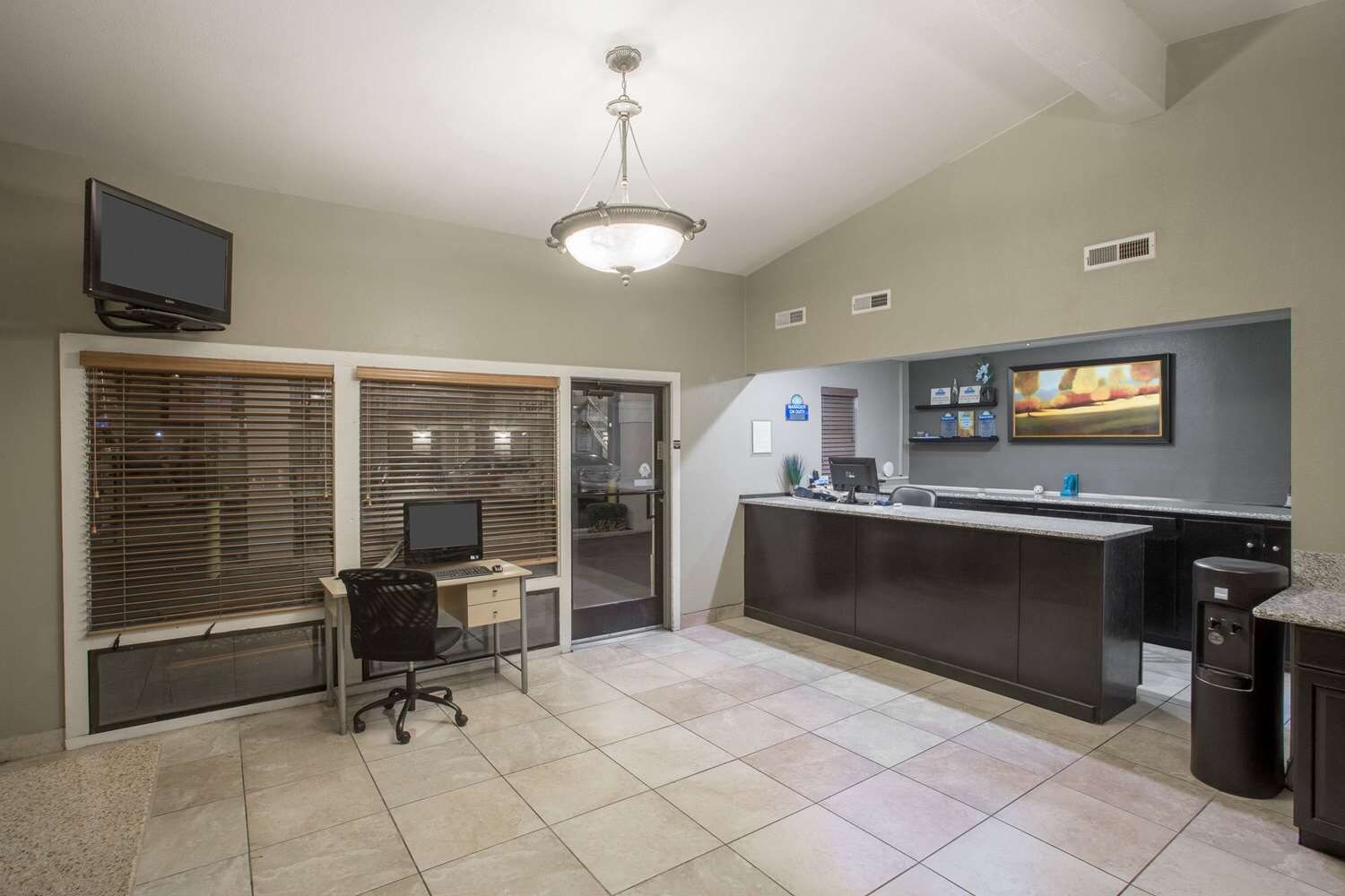 A modern kitchen with a large island, a built-in oven, and a flat-screen TV mounted above the counter.