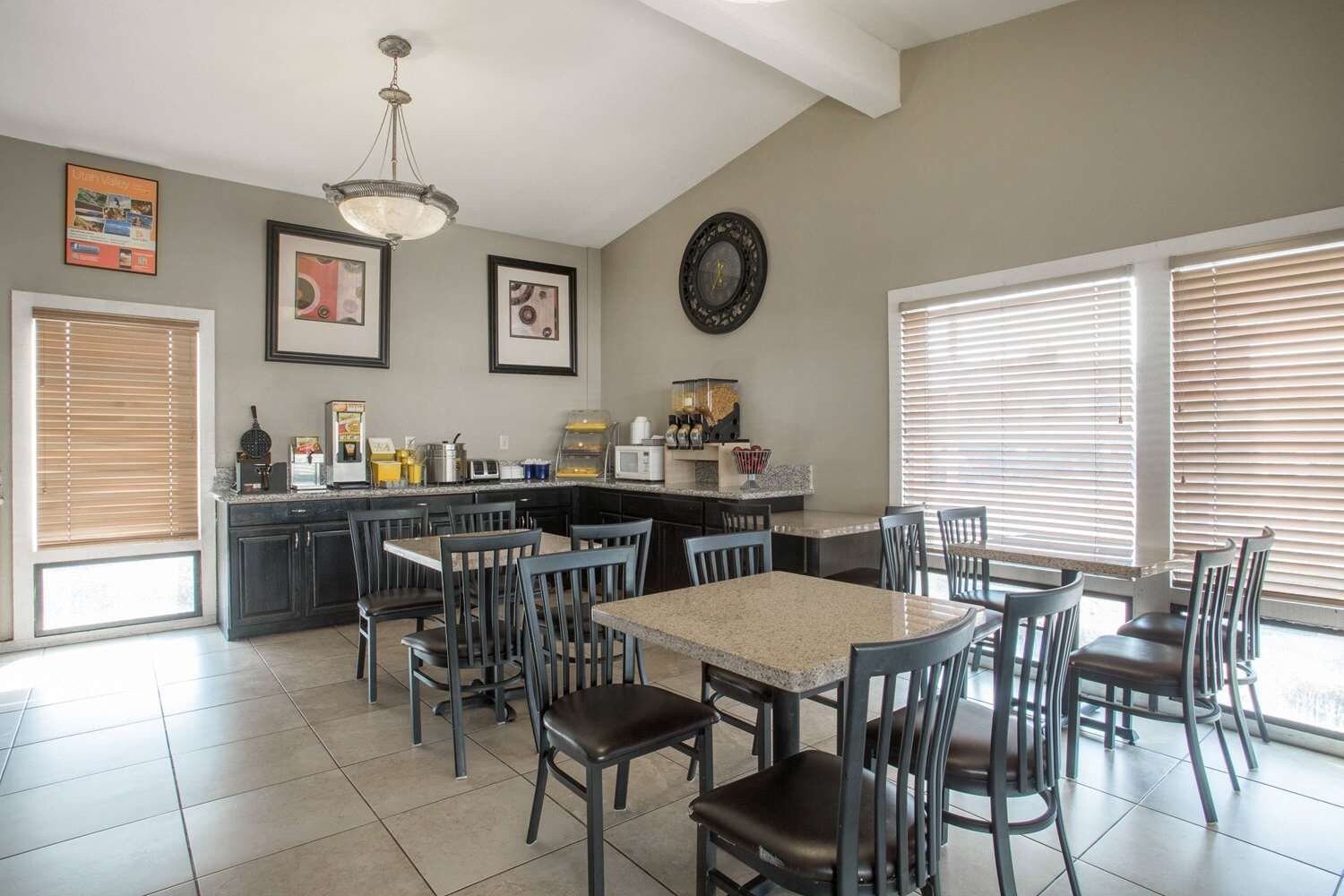 A kitchen with a dining area, featuring a central island, chairs, and a clock on the wall.