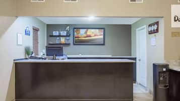 A kitchen with a central island, a coffee machine, and a clock on the wall.