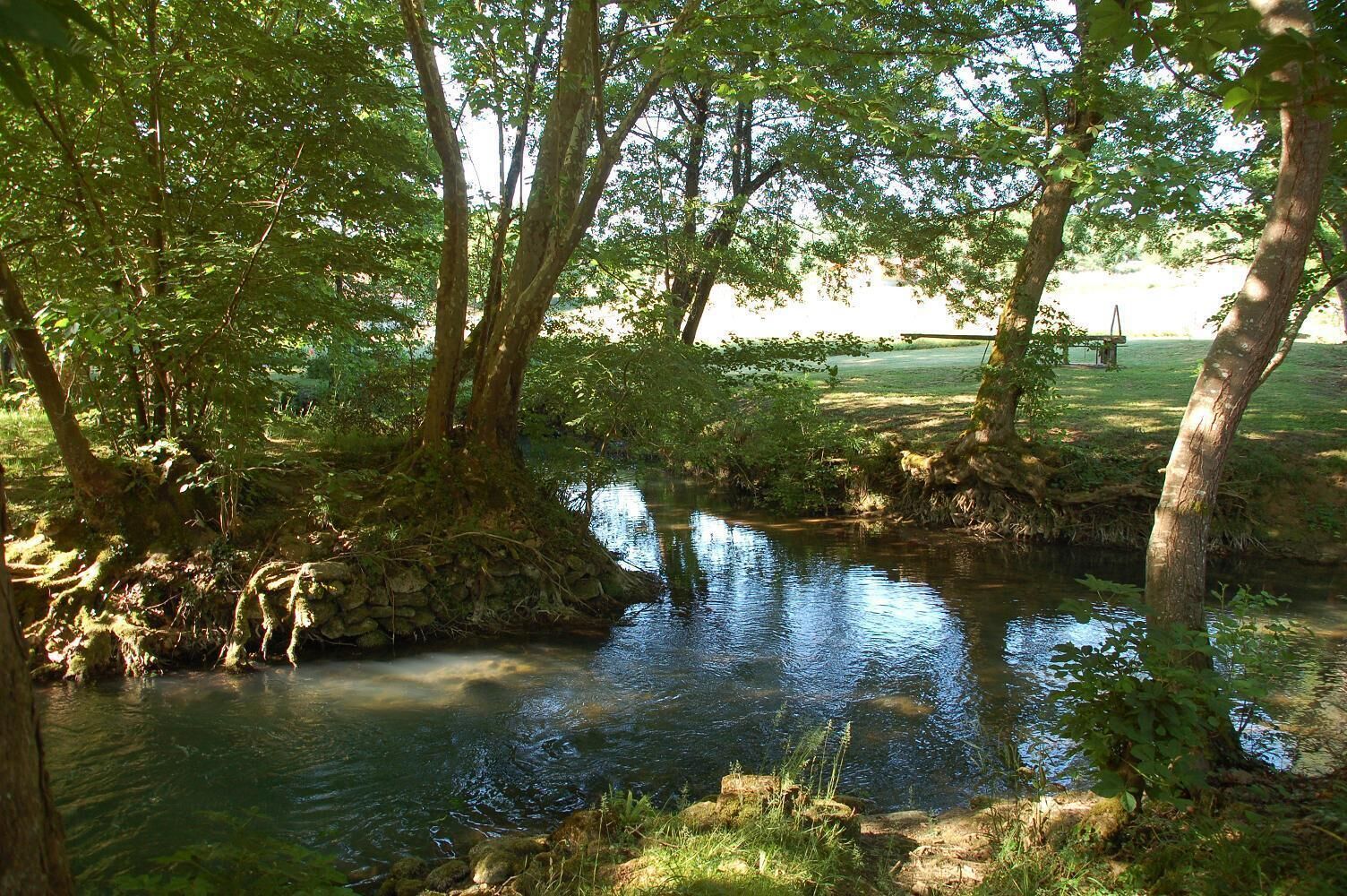 A serene river with trees and a stone structure.