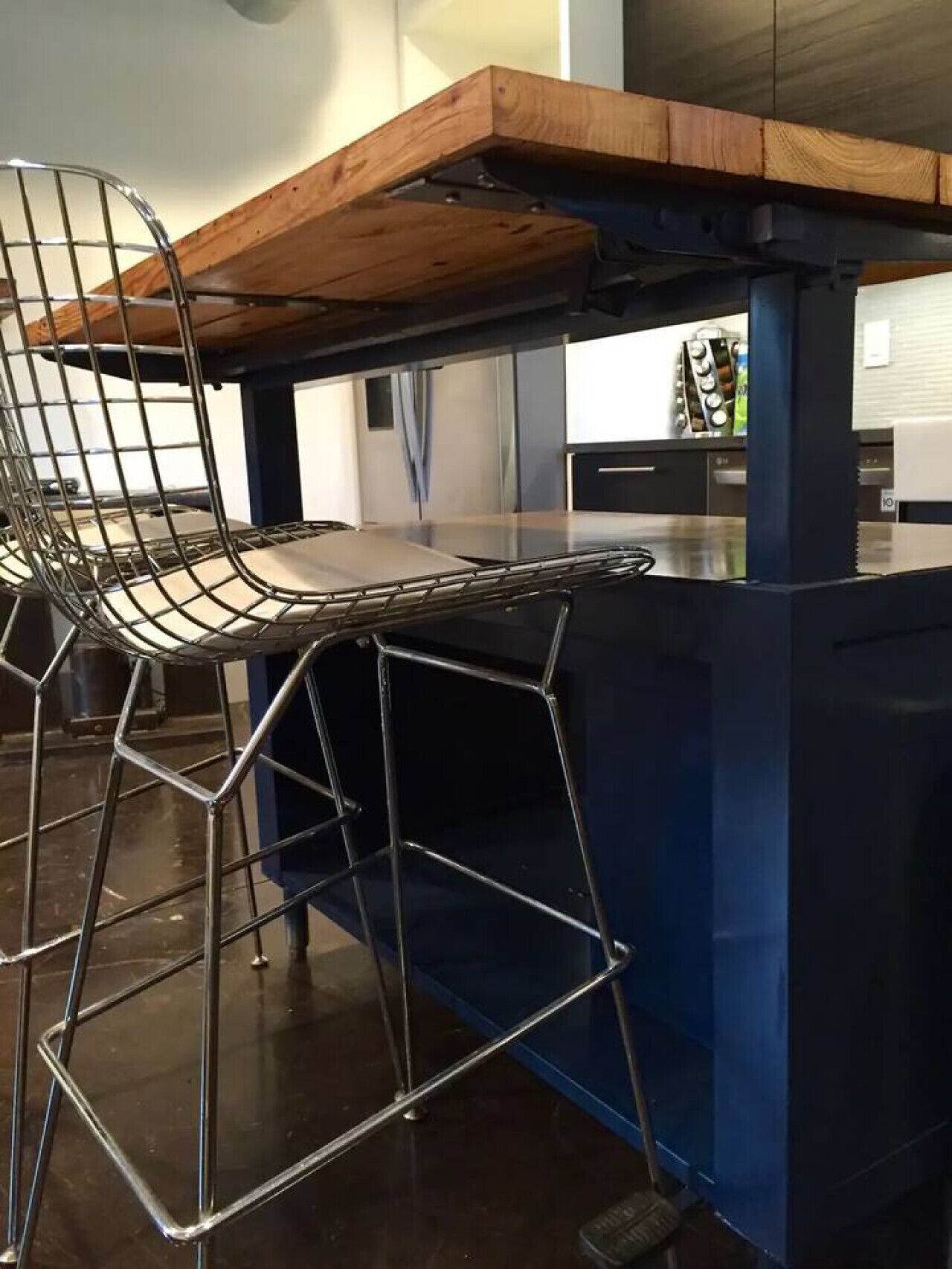 A kitchen with a wooden countertop, a metal chair, and a blue cabinet.