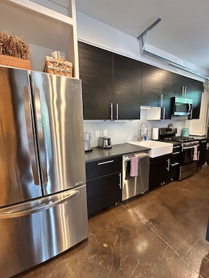 A modern kitchen with stainless steel appliances, black cabinets, and a tiled backsplash. - Chic Garage Unit, Wifi, Close to Pullman Yds (Atlanta)