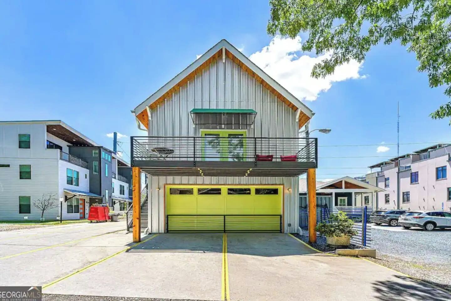Een gebouw met twee verdiepingen, een groene garageklep, een balkon op de bovenverdieping en een modern ontwerp.