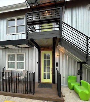 A two-story building with a balcony, a yellow door, and green seating. - Chic Garage Unit, Wifi, Close to Pullman Yds (Atlanta)