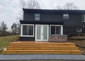 A two-story house with a deck, a sliding glass door, and a large outdoor heater.