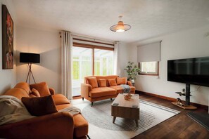 Un salon avec un canapé, une table basse, un téléviseur et une plante.
