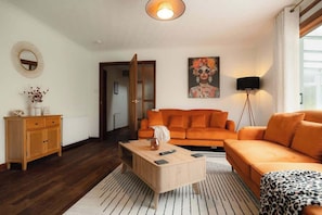 Un salon moderne avec un canapé, une table basse et des œuvres d’art accrochées au mur.