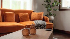 Un salon avec un canapé orange, une table basse en bois et une plante en pot.
