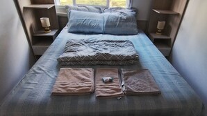 A narrow single bed with a blue and gray bedspread, two pillows, and a folded blanket. - Great location, Caxias do Sul (Caxias do Sul)