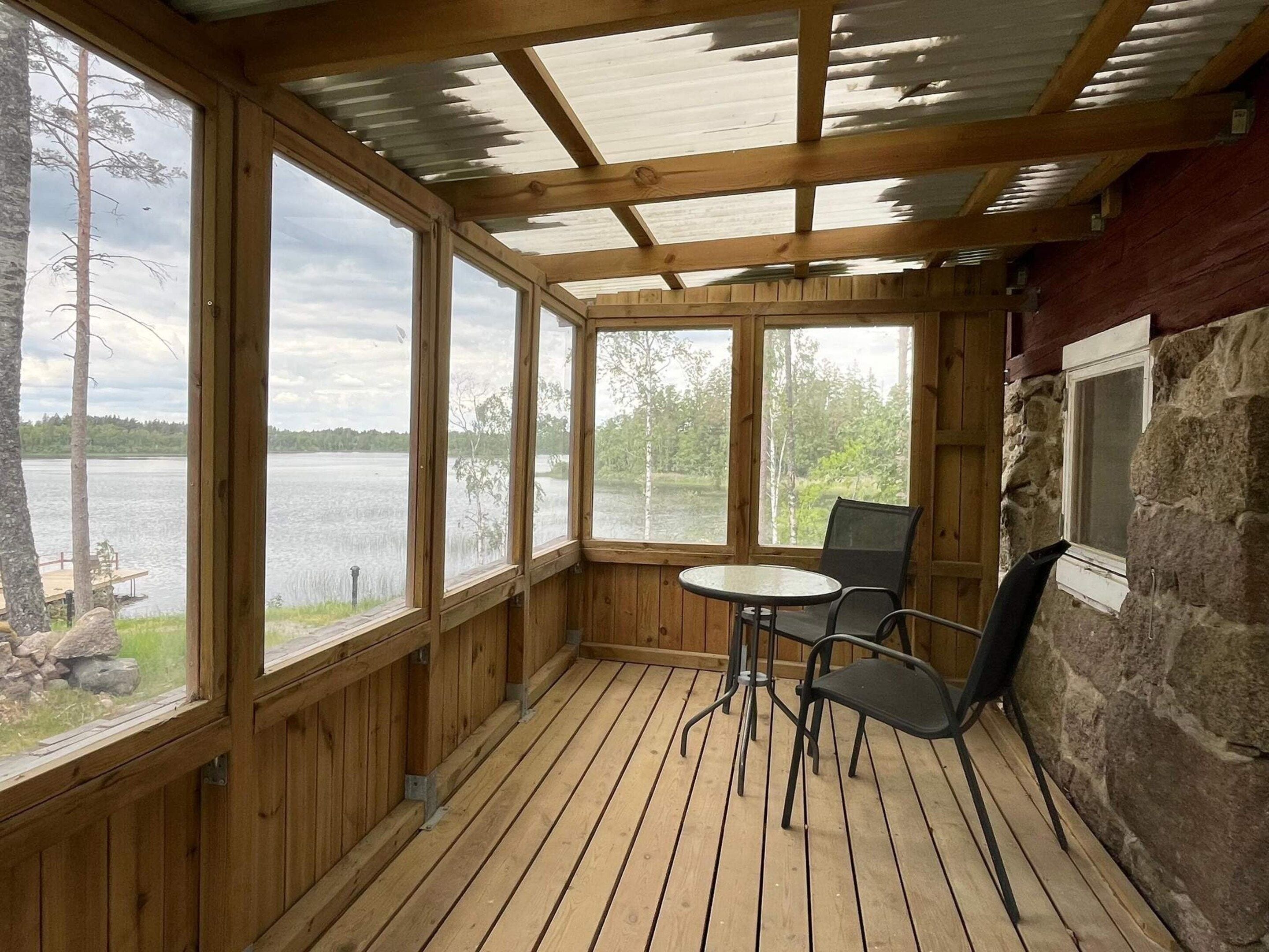 Een houten terras met een tafel en stoelen, met uitzicht op een meer.