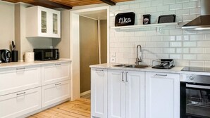A modern kitchen with white cabinets, a microwave, a toaster, and a stove. - 4 Star Holiday Home in Emmaboda (Emmaboda)