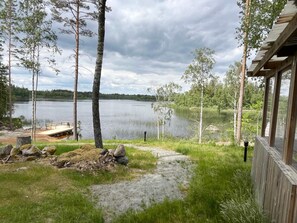 Una cabaña junto al lago con un muelle, rodeada de árboles y vistas al lago.