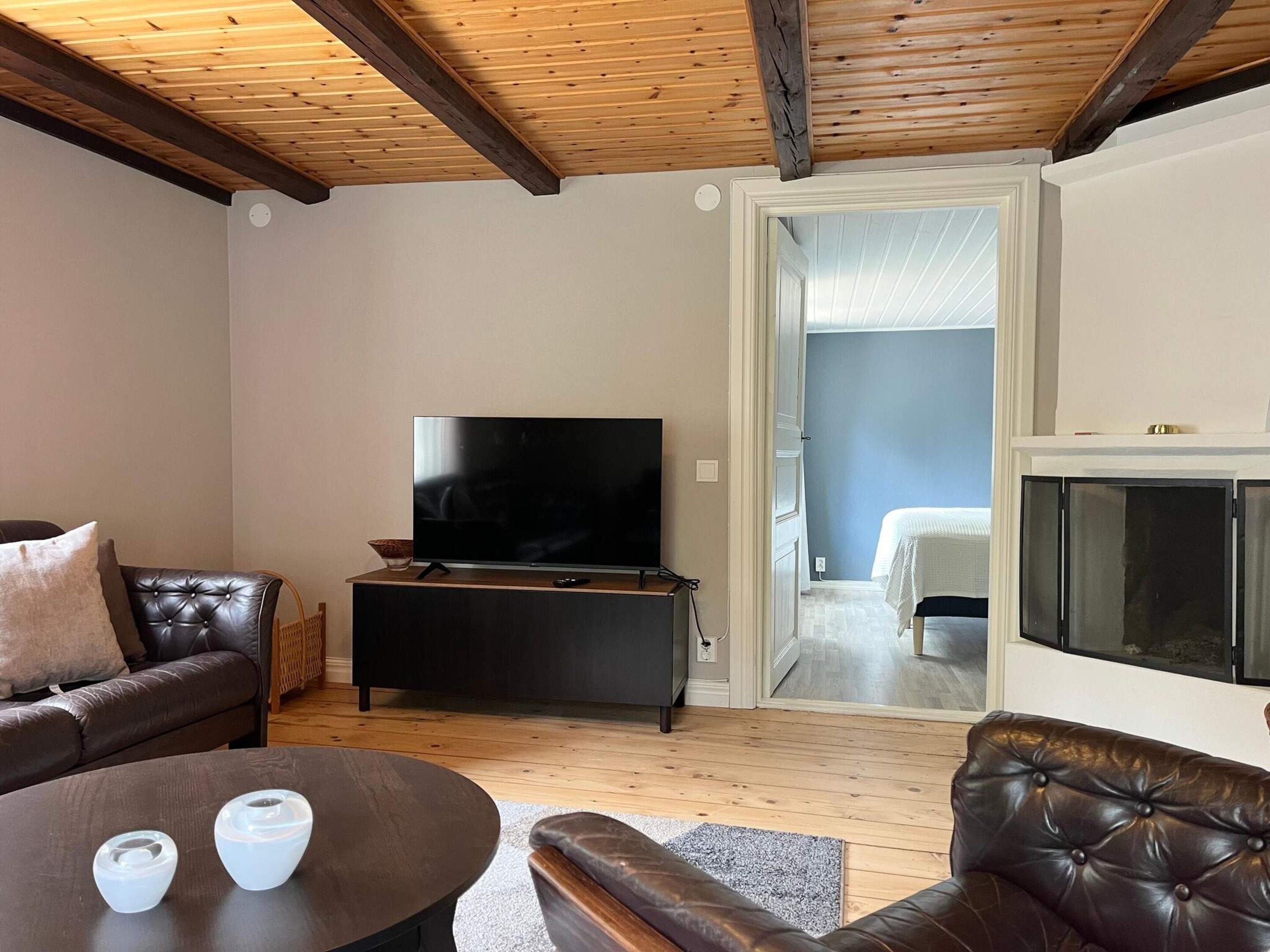 A living room with a flat-screen TV, leather sofas, a coffee table, and a fireplace.
