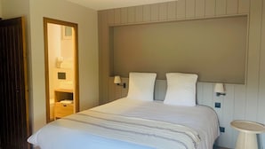 Uma cama bem arrumada com cabeceira, abajures e uma pequena mesa de cabeceira.