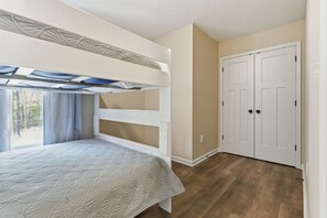 Un dormitorio con literas, un armario y una ventana con cortinas.