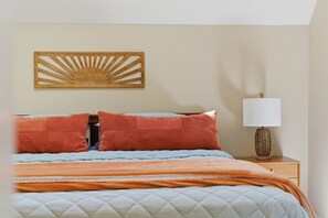 Un lit avec une couverture matelassée, deux oreillers, une lampe de chevet et un élément décoratif fixé au mur.