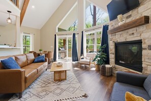 Un salón amplio con chimenea, ventanas grandes y techo alto.