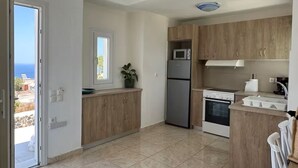 Una cucina moderna con frigorifero, microonde, forno e pensili in legno.