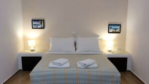 Una camera d'hotel con un letto, due comodini, due lampade e due quadri appesi alle pareti.