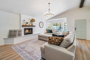 Ein Wohnzimmer mit Kamin, Sofa und großem Fenster.