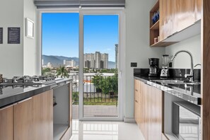 A modern kitchen with a view of high-rise buildings and mountains. - Stylish Zoho Skies 2-BDR, Rooftop Pool + Parking (Puerto Vallarta)