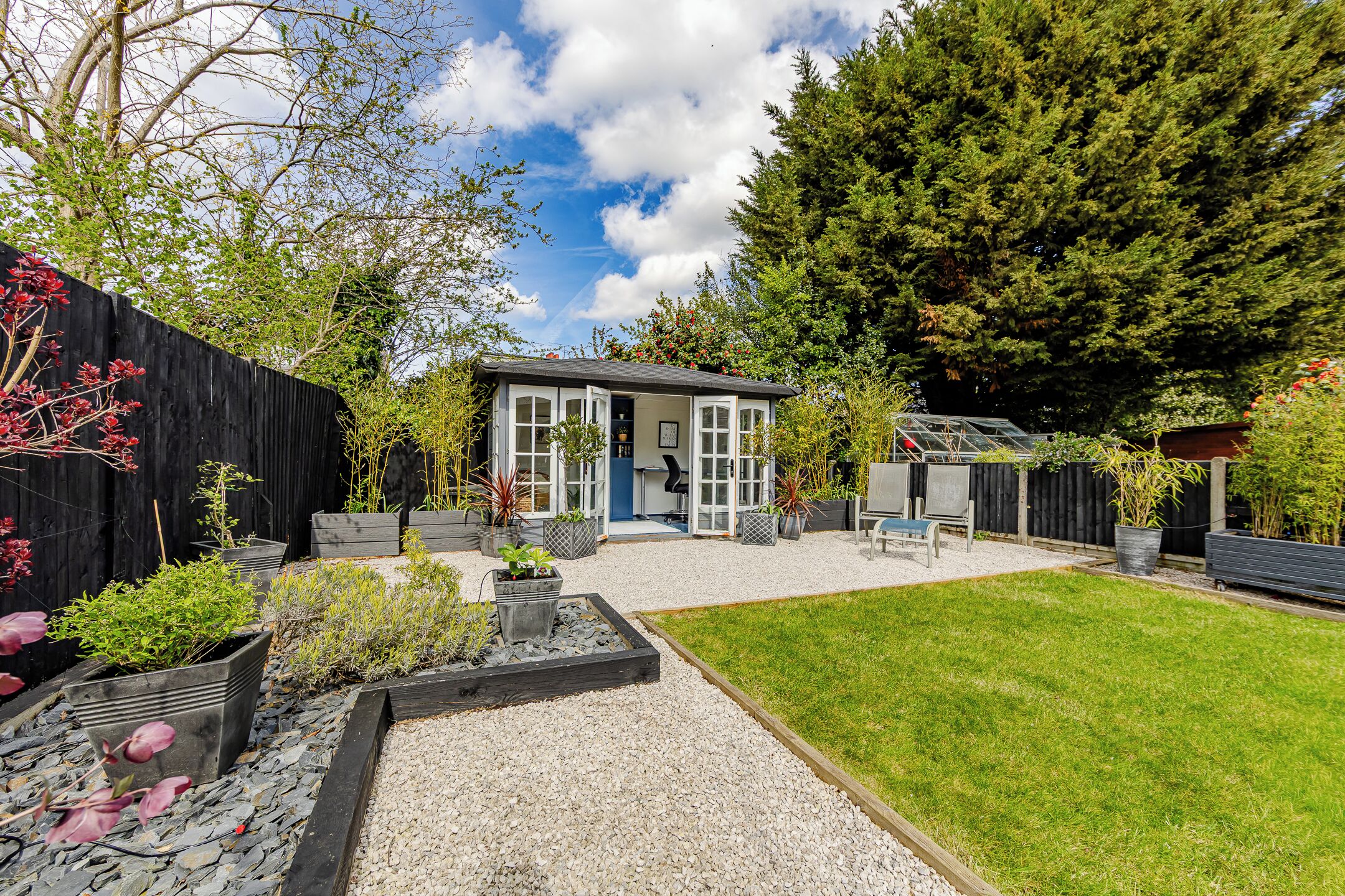 A house with a small garden, a wooden deck, and a fenced area.