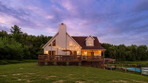 A two-story house with a wooden deck, a swimming pool, and a large yard.