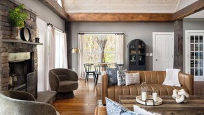 A cozy living room with a fireplace, a sofa, a dining table, and a bookshelf.