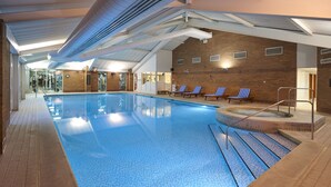An indoor swimming pool with clear blue water, a sunlit ceiling, and a brick wall. - Doubletree Newbury North (Newbury)